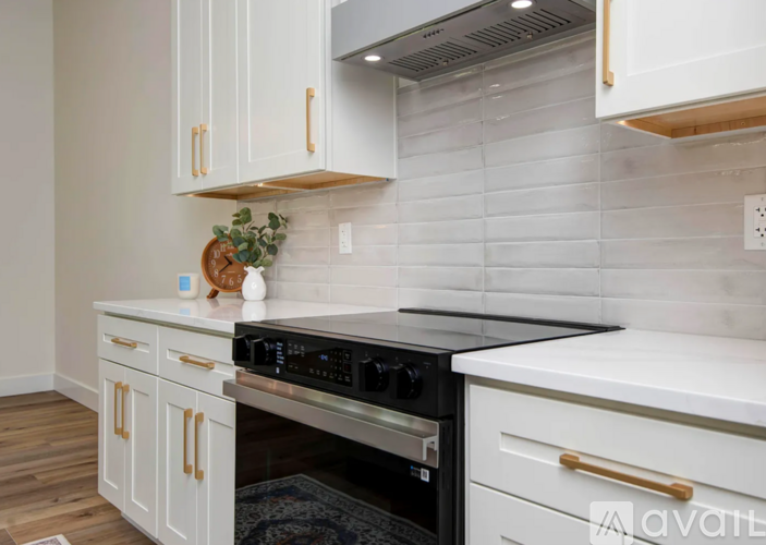 A kitchen with white cabinets and a black stove top oven.