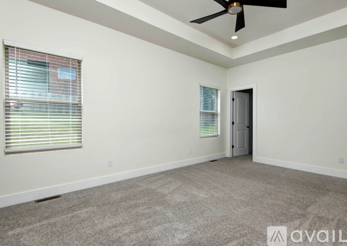 A spacious room with a ceiling fan and carpeted floor.