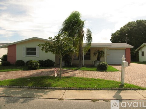 A house with a red and white exterior and a palm tree in front.