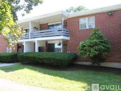 A red brick building with a balcony and a tree in front.