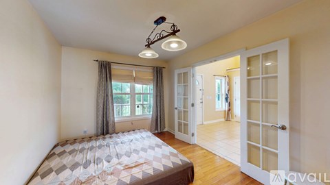 A bedroom with a bed, a window with curtains, and a chandelier.