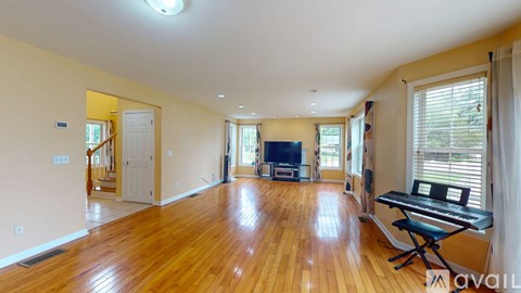 A spacious living room with a piano and a television.
