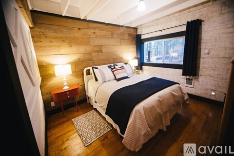 A bedroom with a bed, a nightstand, and a window.