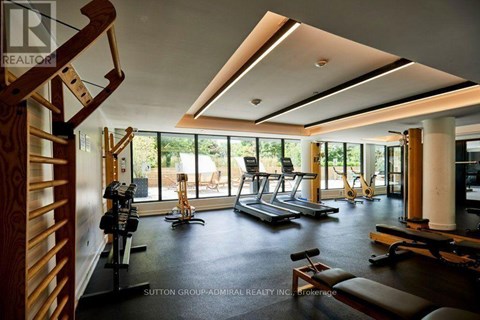 A gym with a row of treadmills and a row of stationary bikes.