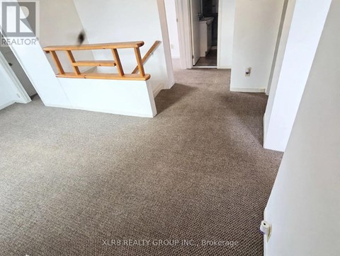 A carpeted room with a staircase leading to the second floor.