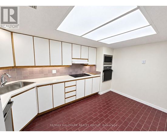 A kitchen with white cabinets and a red tile floor.