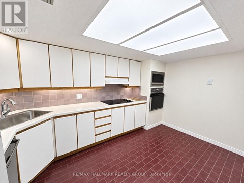 A kitchen with white cabinets and a red tile floor.