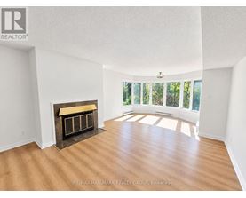 A spacious room with a fireplace and wooden flooring.