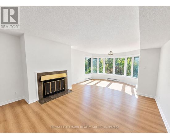 A spacious room with a fireplace and wooden flooring.