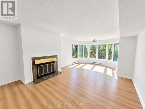 A spacious room with a fireplace and wooden flooring.