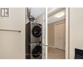 A realtor photo of a room with a washer and dryer stacked on top of each other.