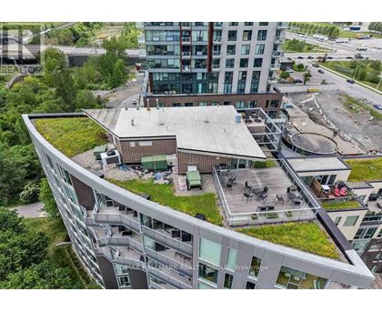 A modern building with a green roof and a parking lot in front.