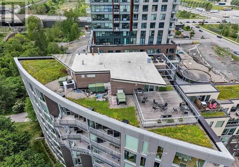 A modern building with a green roof and a parking lot in front.
