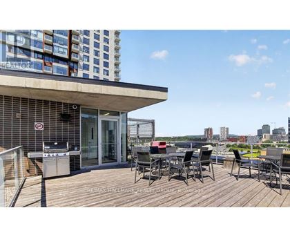 A balcony with a table and chairs overlooks a cityscape.