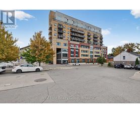 A white car is parked in a lot in front of a multi-story apartment building.
