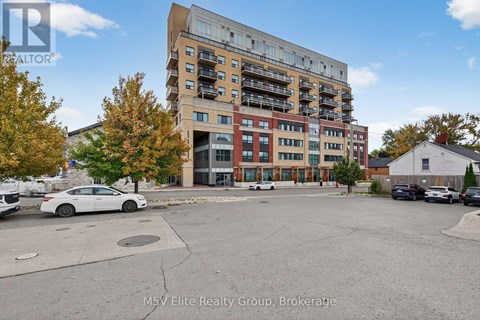 A white car is parked in a lot in front of a multi-story apartment building.
