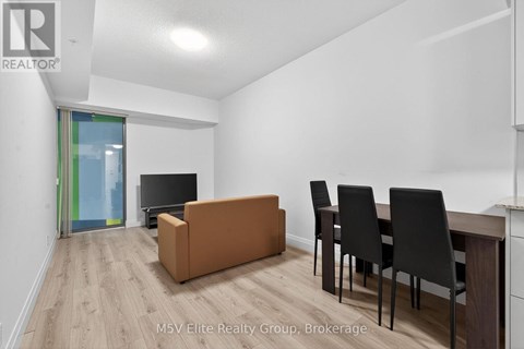 A living room with a brown sofa, black chairs, and a television.
