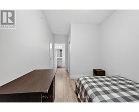 A bedroom with a bed, a table, and a chair.