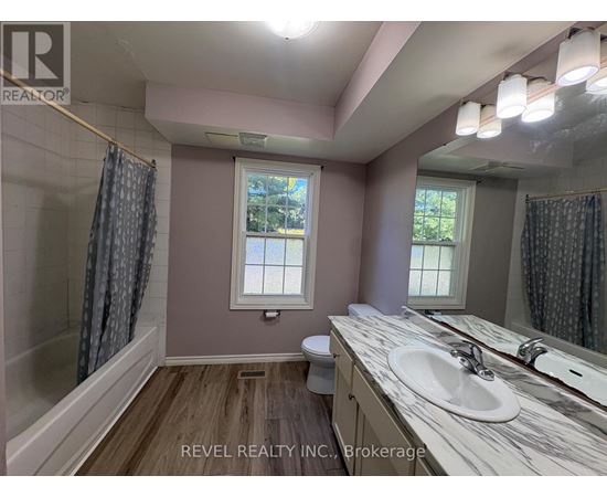 A bathroom with a marble countertop and a window with a view of trees.