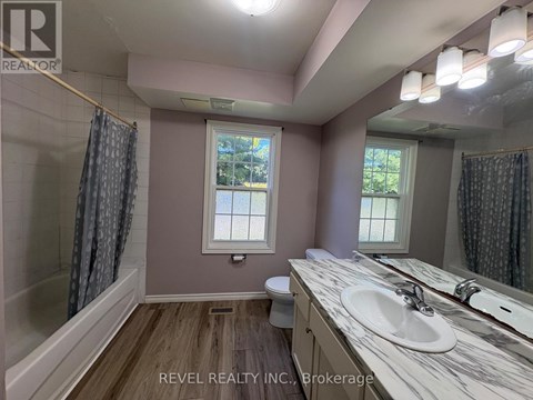 A bathroom with a marble countertop and a window with a view of trees.