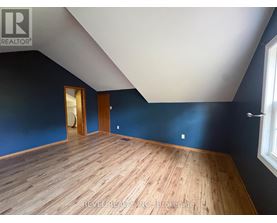 A room with wooden flooring and a window on the right side.