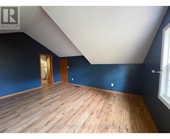A room with wooden flooring and a window on the right side.