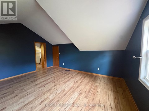 A room with wooden flooring and a window on the right side.