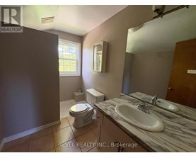 A bathroom with a toilet, sink, and mirror.