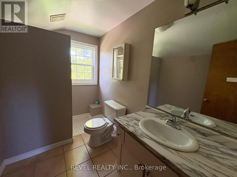 A bathroom with a toilet, sink, and mirror.