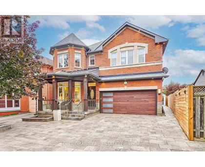 A red brick house with a garage door and a driveway.