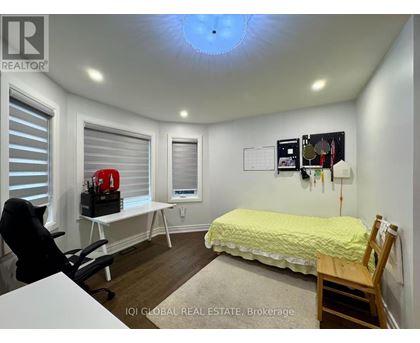 A bedroom with a bed, desk, chair, and window with blinds.