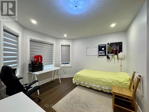 A bedroom with a bed, desk, chair, and window with blinds.
