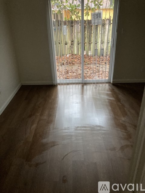 A room with wooden flooring and a sliding glass door leading outside.