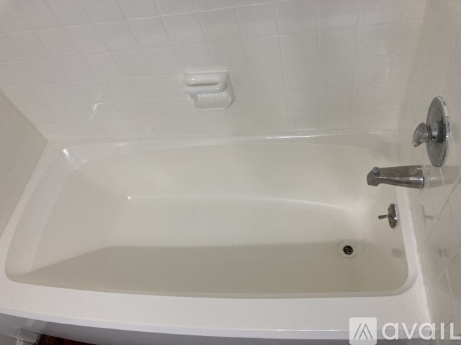 A white bathtub with a silver faucet and a white shower head.