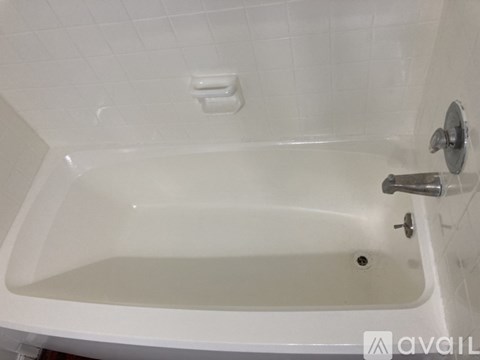 A white bathtub with a silver faucet and a white shower head.
