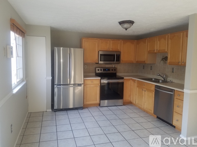A kitchen with wooden cabinets and a stainless steel refrigerator.