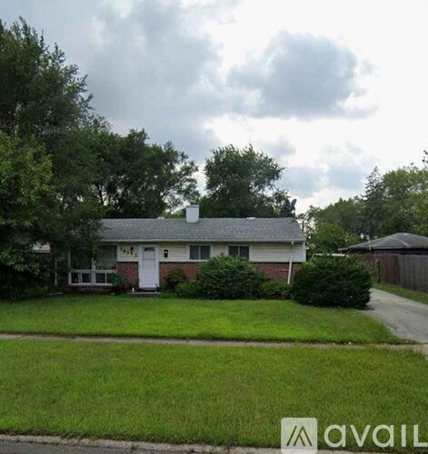 A house with a white door and a small porch is surrounded by greenery.