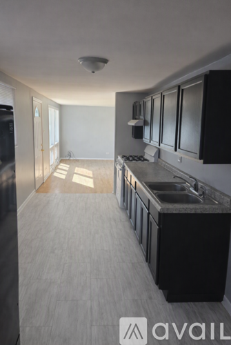 A kitchen with black cabinets and a grey floor.