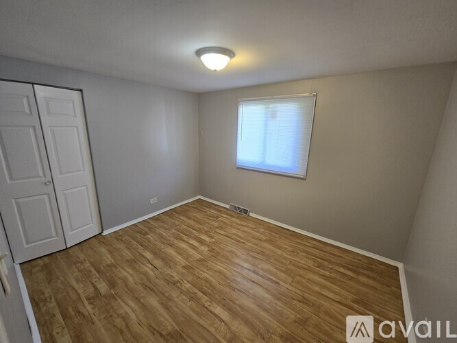 A room with wooden flooring and a window with blinds.