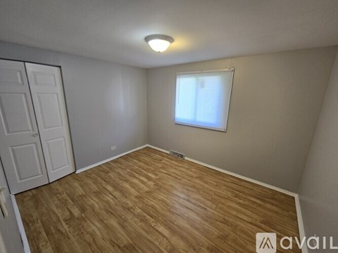 A room with wooden flooring and a window with blinds.