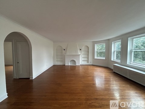 A large empty room with wooden floors and white walls.