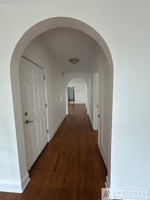 A long hallway with white walls and wood floors.