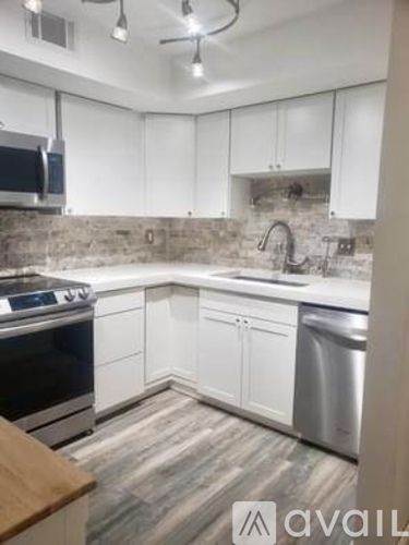 A kitchen with white cabinets and a wooden island.