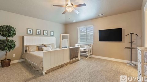 A bedroom with a large bed, a crib, and a television.