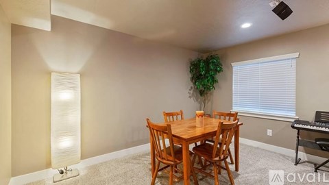 A dining room with a wooden table and chairs, a piano, and a light column.