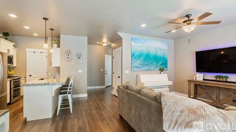 A modern kitchen with a dining area and a living room with a couch and a television.