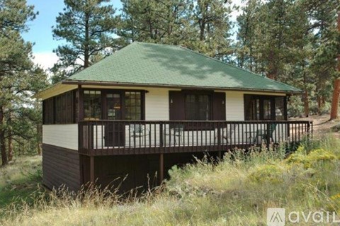 A house with a green roof is surrounded by trees and grass.