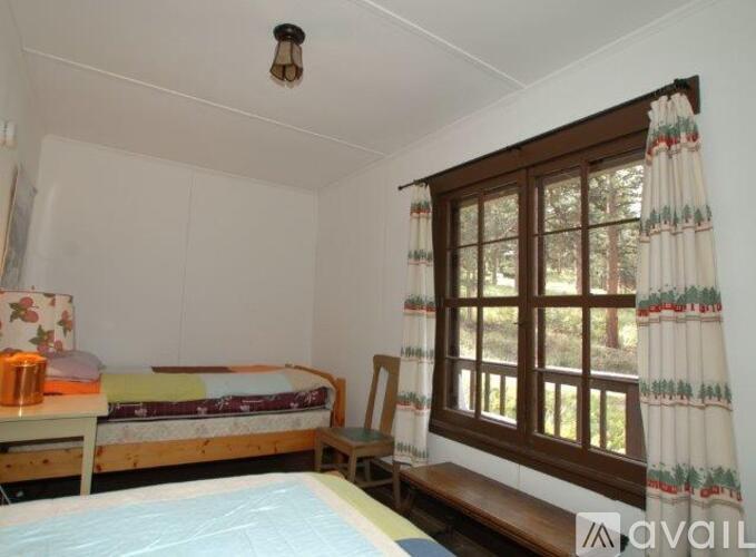 A bedroom with a bed, a chair, and a window with curtains.