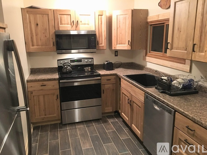 A kitchen with wooden cabinets and a stainless steel refrigerator.