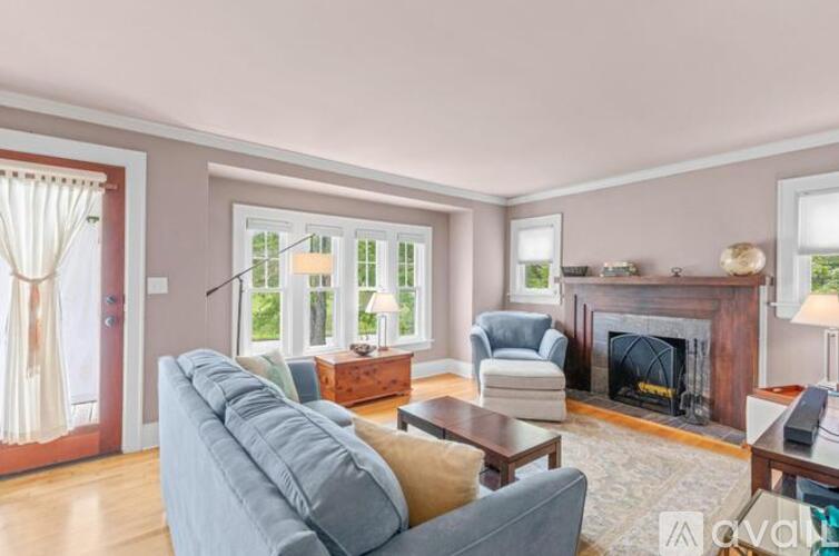 A living room with a grey couch, a fireplace, and a window with curtains.